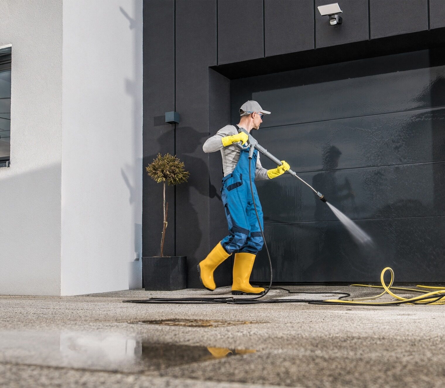 Caucasian Men Pressure Washing His Garage Gate Using Powerful Washer.